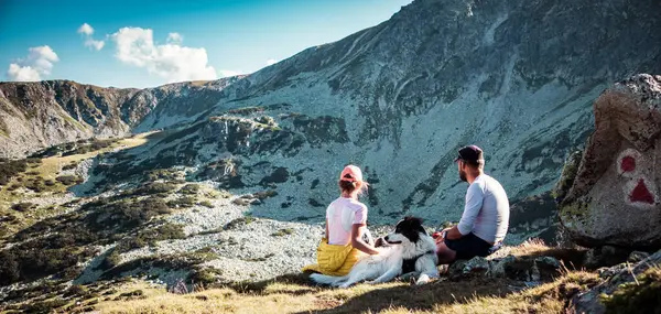 Casal Com Cão Sentado Rochas Admirando Paisagem Montanhosa — Fotografia de Stock