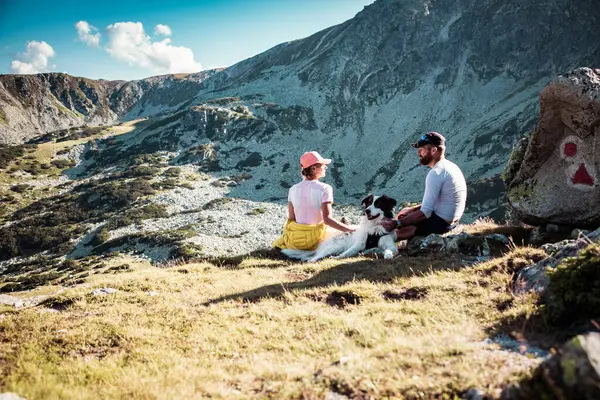 Casal Com Cão Sentado Rochas Admirando Paisagem Montanhosa — Fotografia de Stock