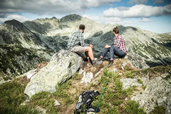 couple sitting on mountain top in amazing summer landscape