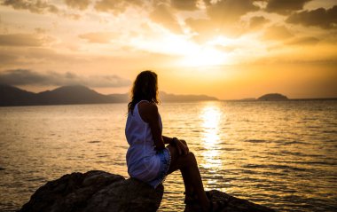 Deniz kenarında gündoğumunun tadını çıkaran kadın.