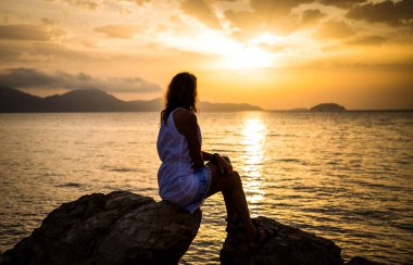 Deniz kenarında gündoğumunun tadını çıkaran kadın.