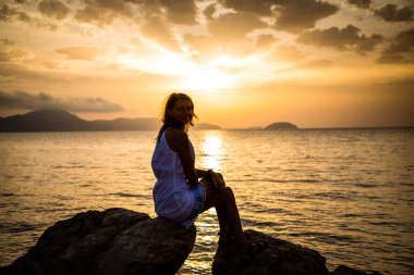 Deniz kenarında gündoğumunun tadını çıkaran kadın.