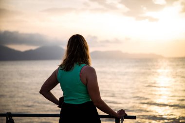 Deniz kenarında gündoğumunun tadını çıkaran kadın.