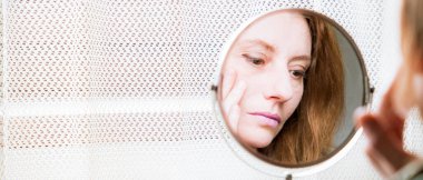 Aynadaki kadın makyaj yapıyor.