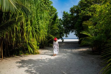 Yemyeşil tropik bitki örtüsünde gezinen bir kadın.