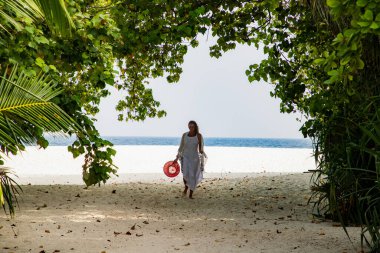 Yemyeşil tropik bitki örtüsünde gezinen bir kadın.