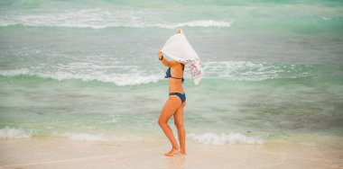 Güzel bir kadın tropik bir plajda eğleniyor.