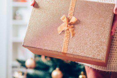 Noel hediyesi kutusunu Noel ışıklarının önünde tutan el.