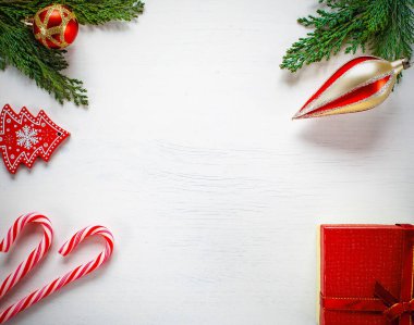 Hediyeli Noel kompozisyonu, köknar ağacı dalları, kırmızı süslemeler ve beyaz arka planda şeker kamışı. Noel, kış, yeni yıl konsepti. Düz konum, üst görünüm, kopyalama alanı