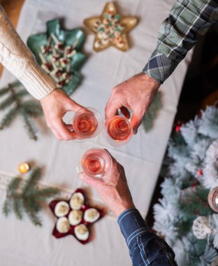 Şenlik masasında şarap kadehleri tutan insanların üst görüntüsü.