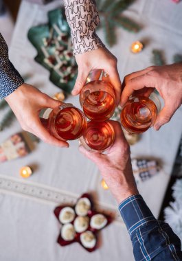 Şenlik masasında şarap kadehleri tutan insanların üst görüntüsü.