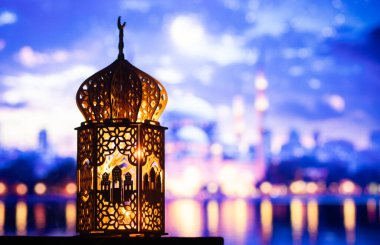 Gece yanan mum ve arka planda cami ile süslenmiş Arapça bir fener. Müslüman kutsal ayı Ramazan Kareem için kutlama kartı.