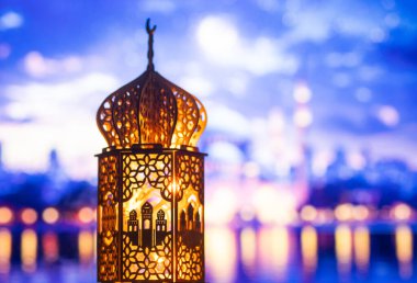 Gece yanan mum ve arka planda cami ile süslenmiş Arapça bir fener. Müslüman kutsal ayı Ramazan Kareem için kutlama kartı.