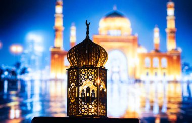 Gece yanan mum ve arka planda cami ile süslenmiş Arapça bir fener. Müslüman kutsal ayı Ramazan Kareem için kutlama kartı.
