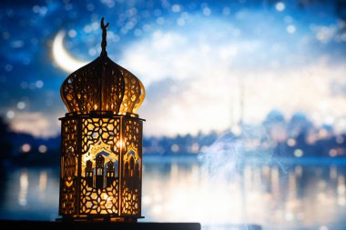 Gece yanan mum ve arka planda cami ile süslenmiş Arapça bir fener. Müslüman kutsal ayı Ramazan Kareem için kutlama kartı.