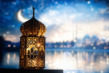 Gece yanan mum ve arka planda cami ile süslenmiş Arapça bir fener. Müslüman kutsal ayı Ramazan Kareem için kutlama kartı.