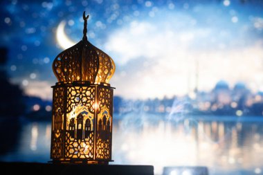 Gece yanan mum ve arka planda cami ile süslenmiş Arapça bir fener. Müslüman kutsal ayı Ramazan Kareem için kutlama kartı.