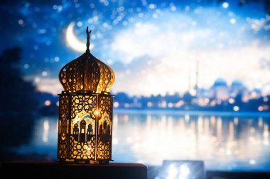 Gece yanan mum ve arka planda cami ile süslenmiş Arapça bir fener. Müslüman kutsal ayı Ramazan Kareem için kutlama kartı.