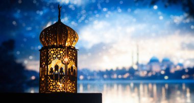 Gece yanan mum ve arka planda cami ile süslenmiş Arapça bir fener. Müslüman kutsal ayı Ramazan Kareem için kutlama kartı.