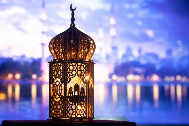 Gece yanan mum ve arka planda cami ile süslenmiş Arapça bir fener. Müslüman kutsal ayı Ramazan Kareem için kutlama kartı.