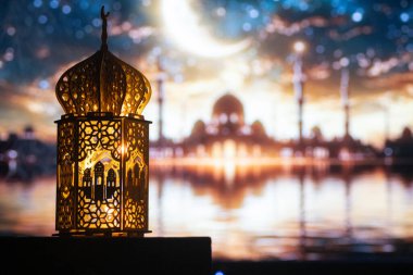 Gece yanan mum ve arka planda cami ile süslenmiş Arapça bir fener. Müslüman kutsal ayı Ramazan Kareem için kutlama kartı.