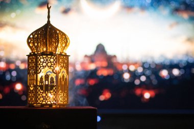 Gece yanan mum ve arka planda cami ile süslenmiş Arapça bir fener. Müslüman kutsal ayı Ramazan Kareem için kutlama kartı.