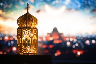 Gece yanan mum ve arka planda cami ile süslenmiş Arapça bir fener. Müslüman kutsal ayı Ramazan Kareem için kutlama kartı.