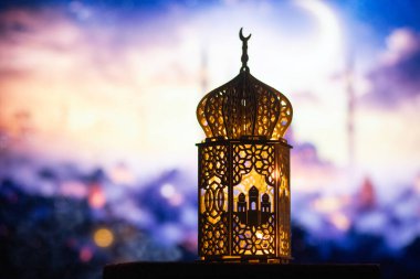 Gece yanan mum ve arka planda cami ile süslenmiş Arapça bir fener. Müslüman kutsal ayı Ramazan Kareem için kutlama kartı.