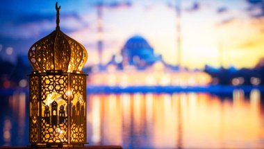 Gece yanan mum ve arka planda cami ile süslenmiş Arapça bir fener. Müslüman kutsal ayı Ramazan Kareem için kutlama kartı.