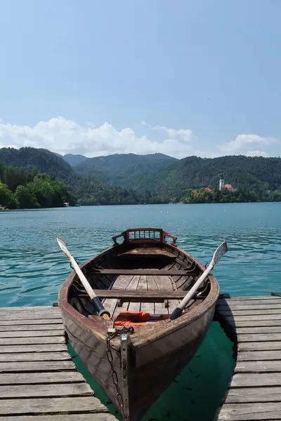 İskeleye demirlemiş geleneksel ahşap bir tekne. Alp arka planıyla Bled Gölü 'nde..