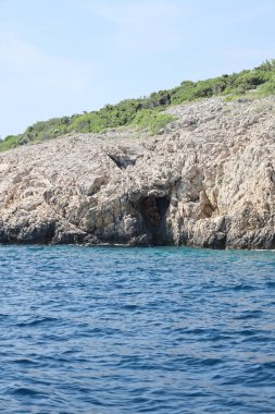 Hırvatistan kıyı şeridinde görünen bir deniz mağarası olan kayalık bir uçurumun yakın çekimi.