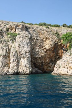 Uzaktaki yüzücülerle birlikte su kenarına inen büyük desenli uçurum..