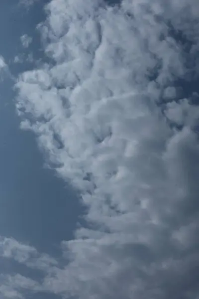 Derin mavi yaz gökyüzüne doğru yükselen dramatik bir dikey bulut oluşumu.