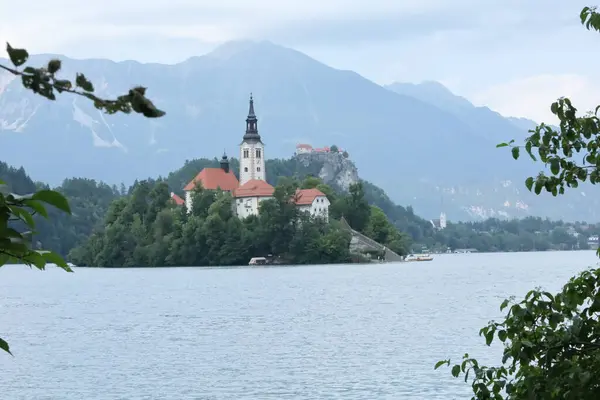 Bled Island ve Bled Castle 'ın geniş açılı dramatik görüntüleri dağlarla çevrili tek bir çerçevede..