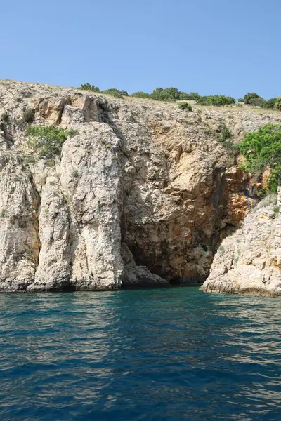 Uzaktaki yüzücülerle birlikte su kenarına inen büyük desenli uçurum..