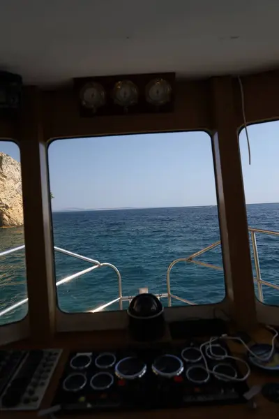 Engebeli bir kireçtaşı kayalığı berrak mavi suyun üzerinde yükseliyor. Parlak, güneşli bir günde yakalanan bu uzak kıyı manzarasının dokuları ve gölgeleri doğal güzelliğini arttırır..