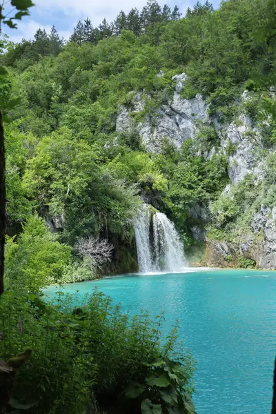 Sersemletici bir şelale kayalık bir uçurumdan ormanla çevrili turkuaz bir göle dökülüyor, yemyeşil yaz yeşiliyle çerçevelenmiş..