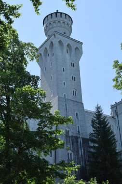 Avrupa 'nın ünlü bir şatosunun parçası olan yeşil ağaçlar tarafından çerçevelenmiş kemerli detaylara sahip yüksek bir taş yapı..