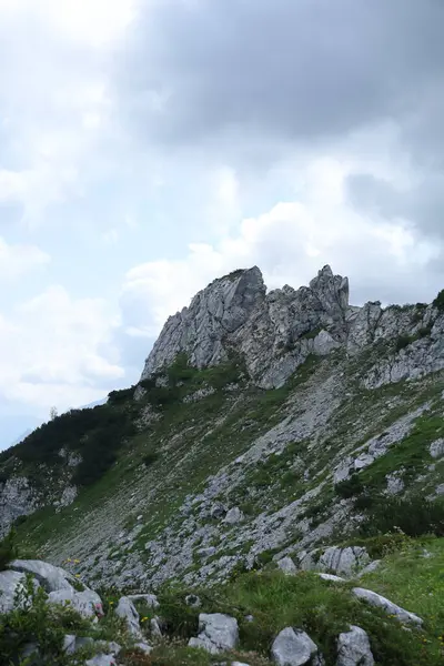 Şiddetli bulutlarla dolu dramatik bir gökyüzünün altındaki keskin kayalık dağ zirvesi alp ihtişamını çağrıştırıyor..