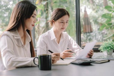 Marketer or analytic manager team dressed in suits working with paper charts and laptops at the meeting room.