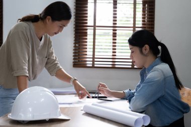 Bir ofiste bir tablet bilgisayardaki bilgileri denetlenirken bir plan mühendisleri tartışmak.