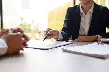 Takım elbiseli kadın emlakçı kontratı imzalamadan önce masa başında alıcı ya da müşteriyle anlaşma, ev fiyatı, finans ve anlaşma konusunda pazarlık yapıyor. İş, ipotek, sigorta kavramı.