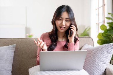 Güzel Asyalı iş kadını, girişimci, ya da günlük kıyafetlerle serbest çalışan kağıt işleri ve dizüstü bilgisayarla evdeki oturma odasında günlük olarak çalışan biri. Evde, iş konsepti.  