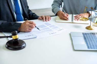 İki avukat veya avukat ellerinde kağıt dosya ve belgelerle masada oturuyorlar ve özenle tartışıp danışmanlık yaparlarken mahkemeye getirilecek önemli dava belgelerini inceliyorlar. Hukuk, adalet kavramı.