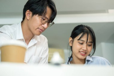 İki erkek ve kadın mühendis ya da mimar çalışma masasında profesyonel ekipmanlarla birlikte çalışarak inşaat projesinin planlarını gösteriyorlar, çiziyorlar, planlıyorlar ve tartışıyorlar..