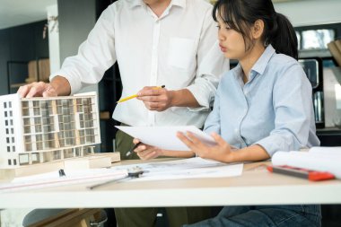 İki erkek ve kadın mühendis ya da mimar ofis işyerinde birlikte çalışarak inşaat projesinin planları ve planları için model arıyorlar..