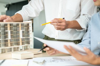 İki erkek ve kadın mühendis ya da mimar ofis işyerinde birlikte çalışarak inşaat projesinin planları ve planları için model arıyorlar..