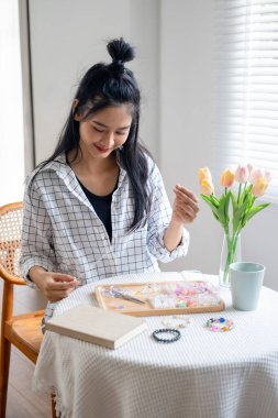 Neşeli ve el yapımı bilezikler yapan genç bir kız.