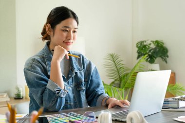 Genç bayan mimar veya iç mimar ofisindeki masasında oturur, dizüstü bilgisayarla çalışır ve tasarım fikirlerini hayata geçirir ve çizelgelerden renkler seçer, tüm projeyi bir kalem tutarken hayal eder ve düşünür.. 