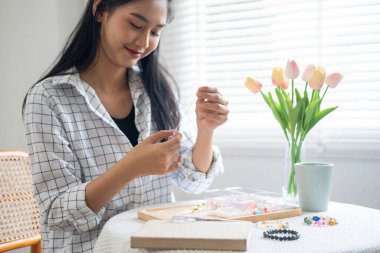 Neşeli ve el yapımı bilezikler yapan genç bir kız.